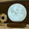 Lunara Levitating Moon Lamp glowing white on wooden base